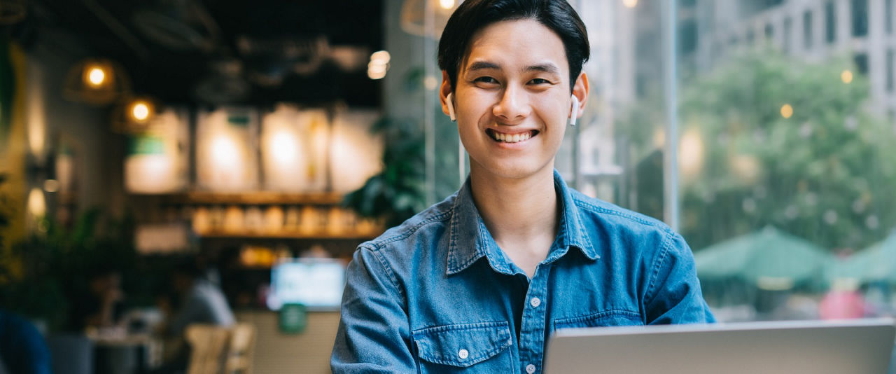  Young man using a laptop in a café, researching life insurance plans