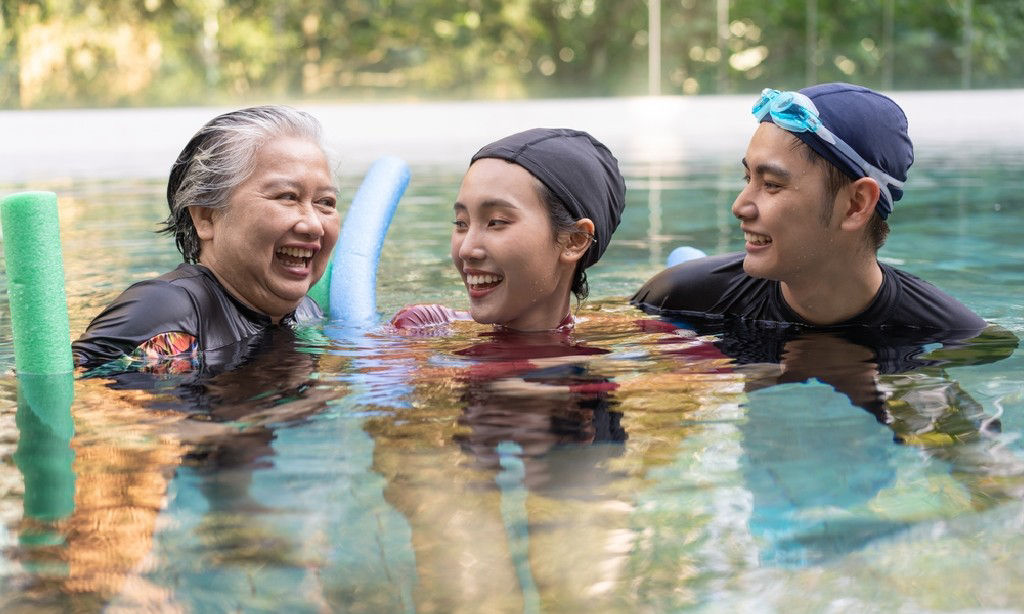 An Asian grandmother swim with her young-adult grandchildren.