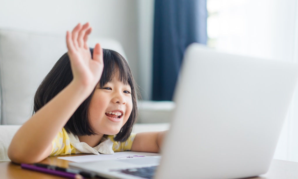 Grade school female student raises her hand during an online class.