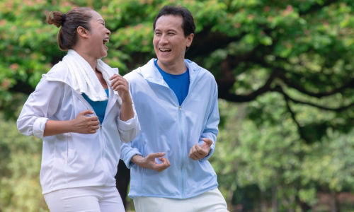 Happy mature Asian couple running in park