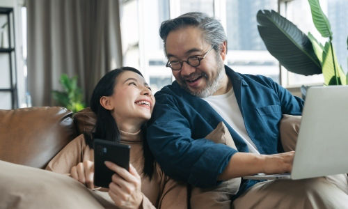 Asian couple in their 40s discuss retirement as they stay on their devices.