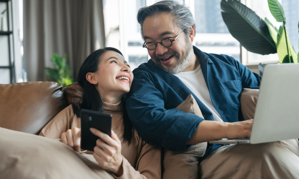 Asian couple in their 40s discuss retirement as they stay on their devices.