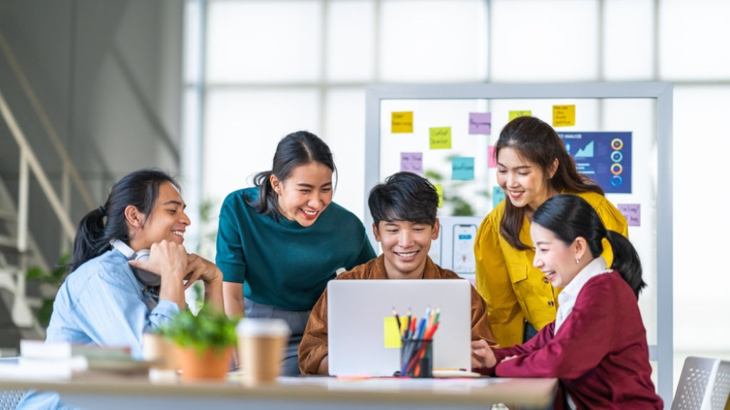 Young Asian employees gathered at a table and working together.