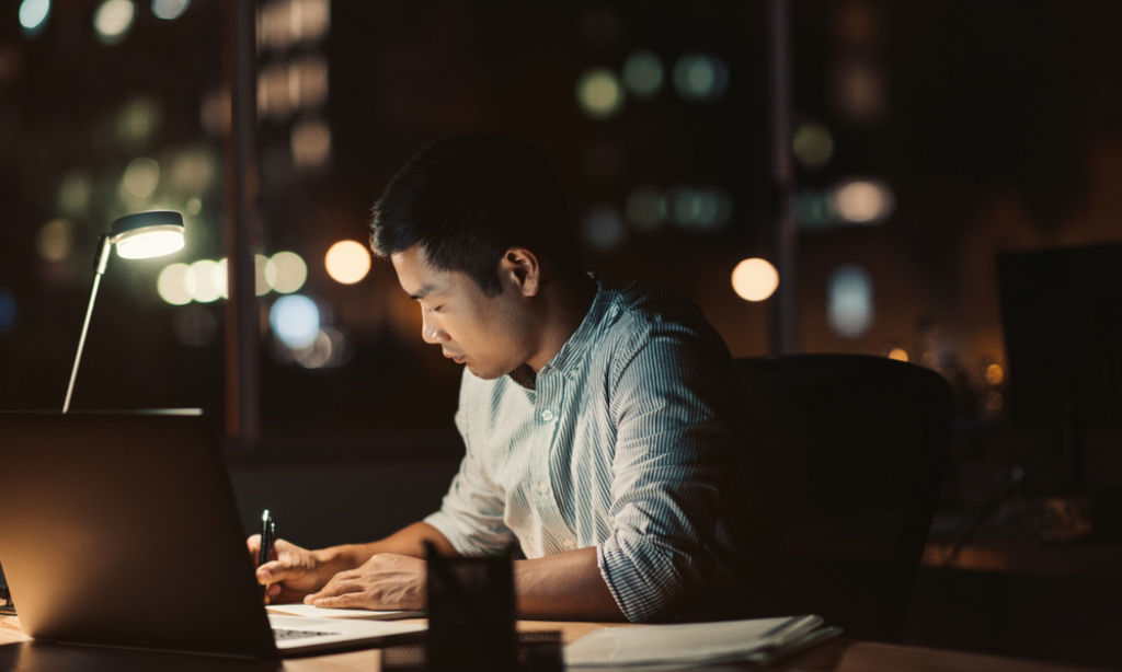 Asian professional notes a family breadwinner concern in his diary.