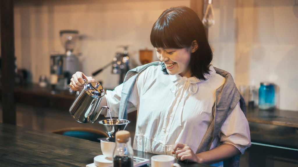 Asian woman brewing coffee.