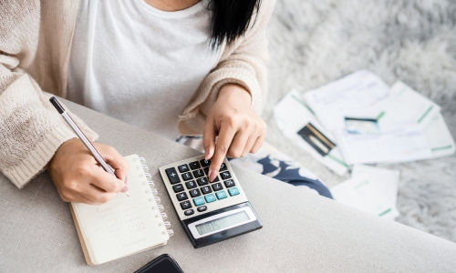 woman computing her budget and expenses with a calculator and notebook