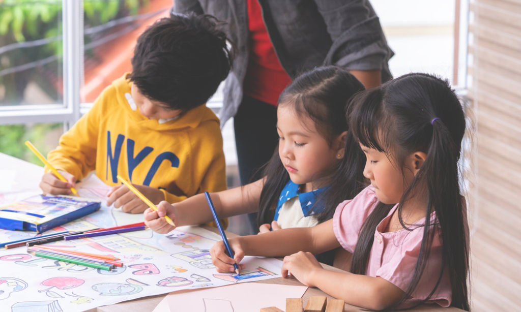 Three children drawing and painting at school